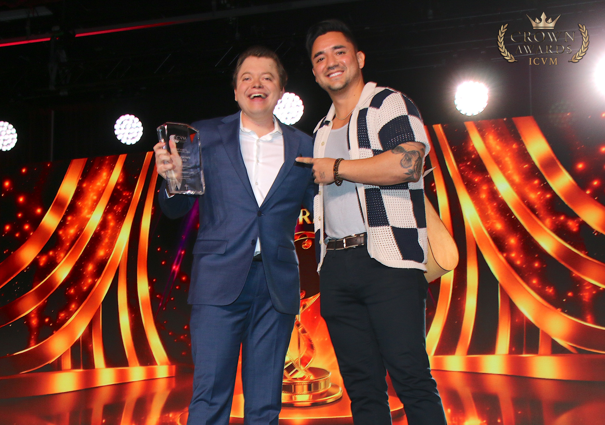 A Crown Award recipient displaying a glass trophy beside a presenter