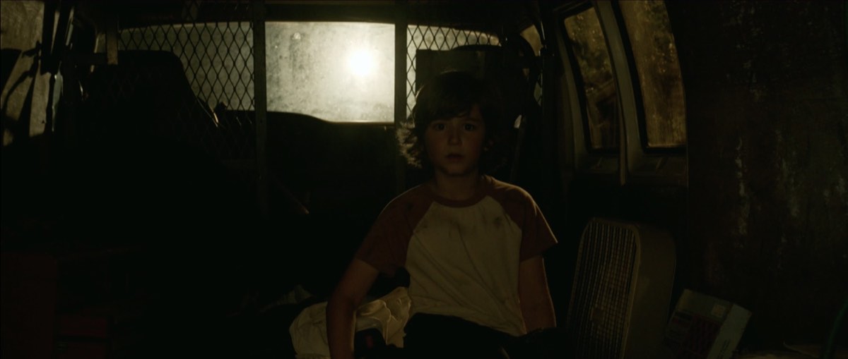Young Mark sits alone in a vehicle in a still from Forgiving the Nightmare